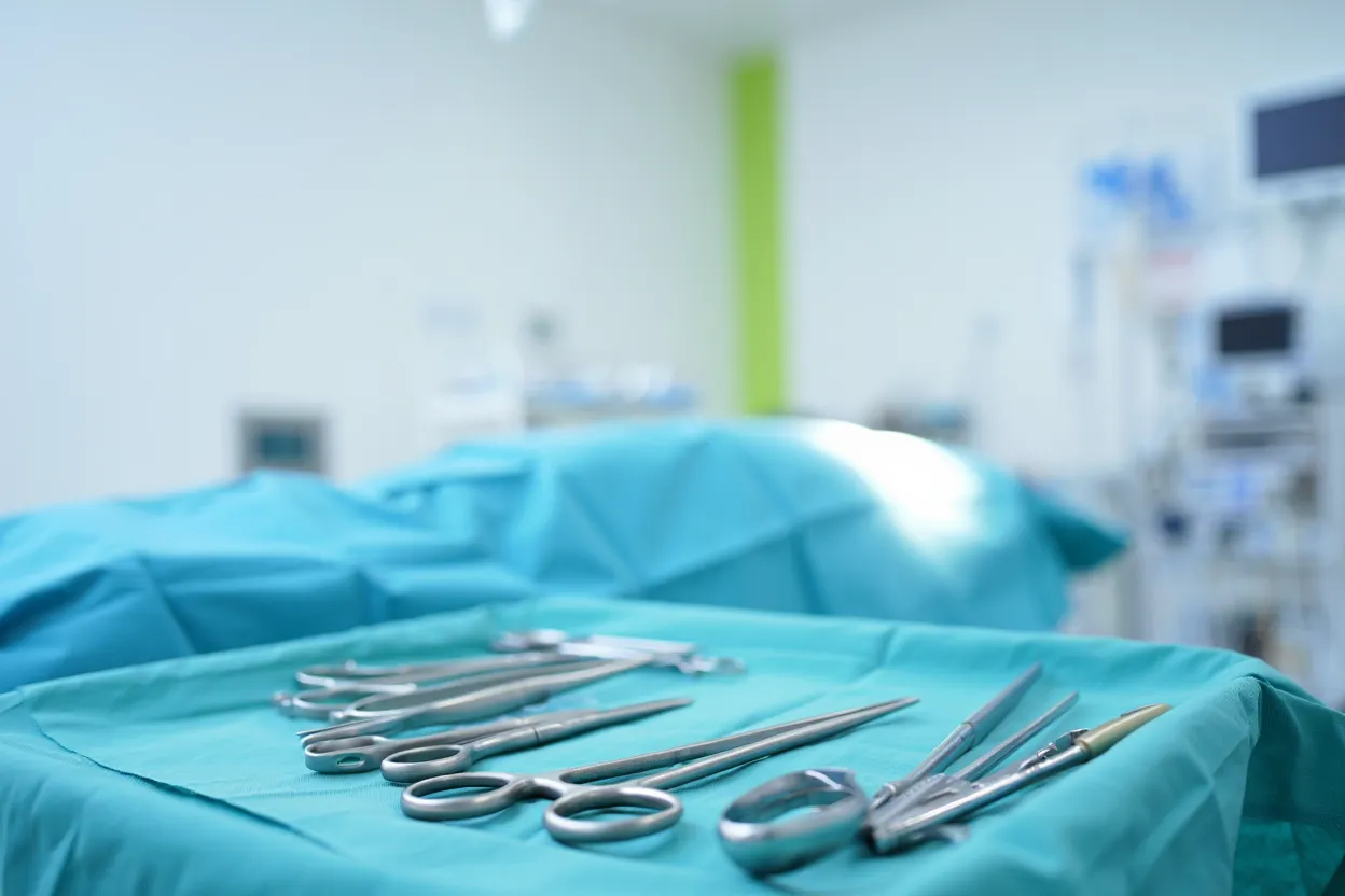 Bloc opératoire avec lumière bleue douce, instruments chirurgicaux stériles posés sur un champ opératoire — illustration de la préparation d'une abdominoplastie sécurisée