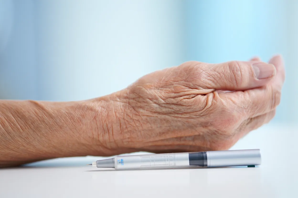 Gros plan de peau d'avant-bras montrant sa texture, à côté d'un stylo injecteur de sémaglutide, lumière médicale bleutée